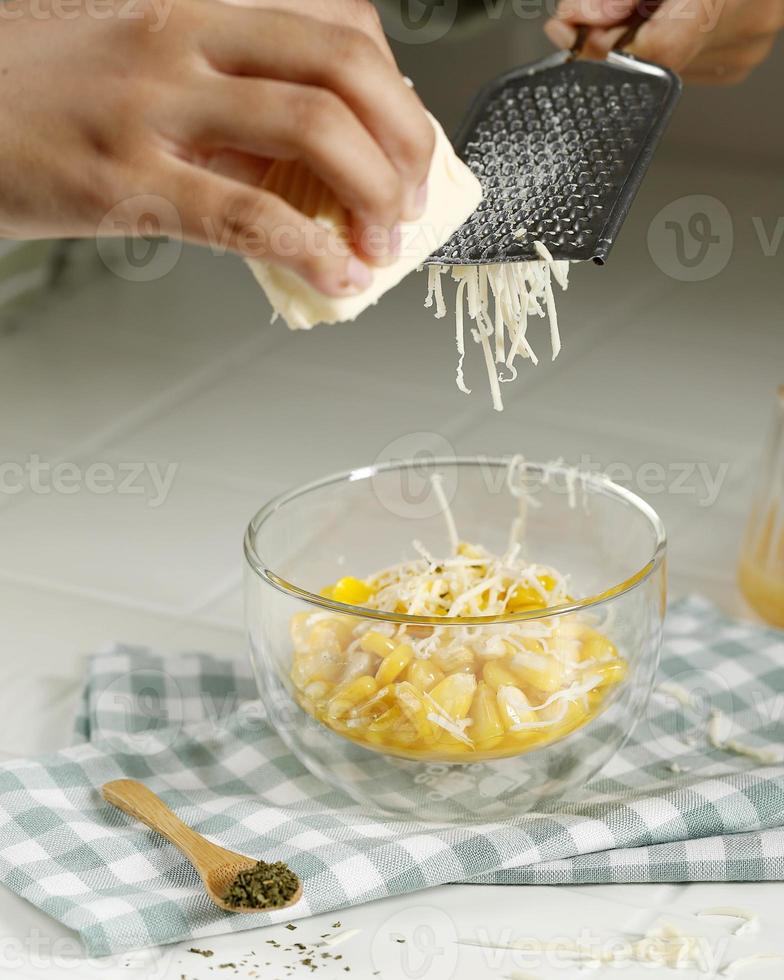 proceso de queso rallado sobre maíz de mantequilla, paso a paso haciendo bocadillos en la cocina foto