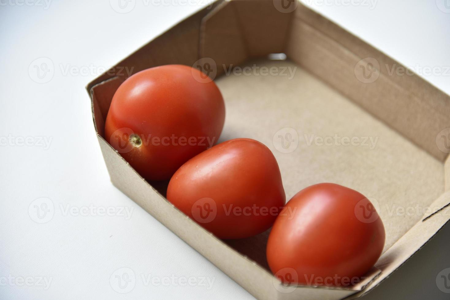 Cardboard box with ripe red tomatoes on a white background photo