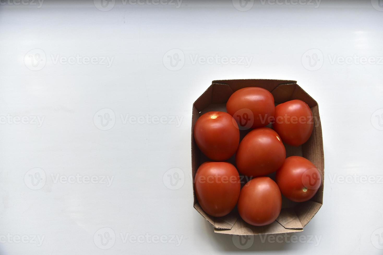 Cardboard box with ripe red tomatoes on a white background photo