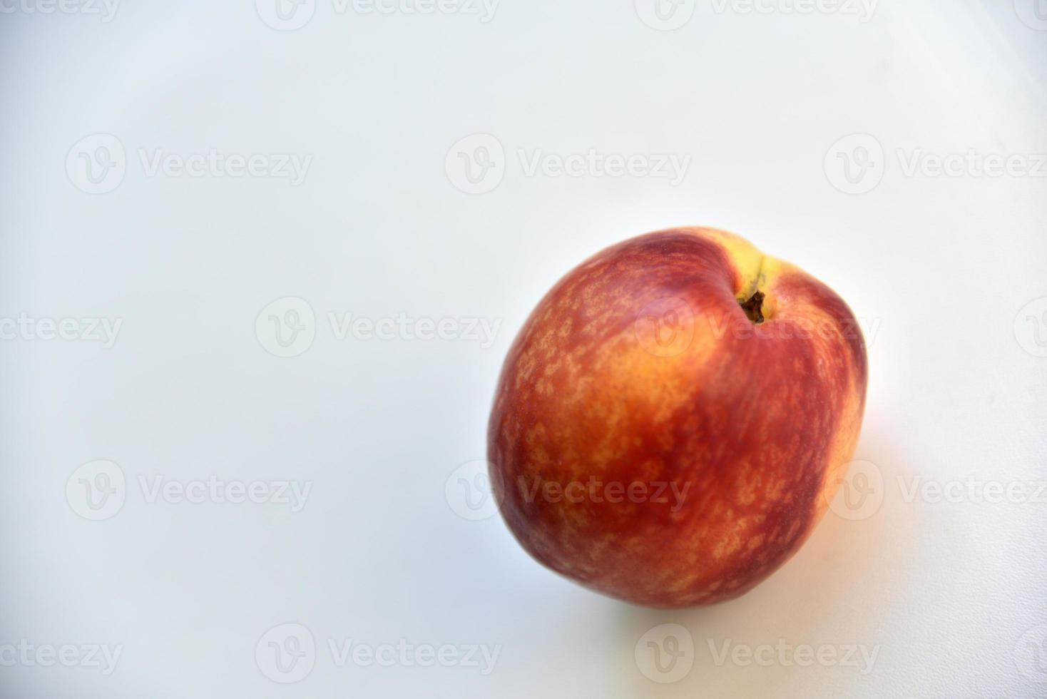 Yellow-red juicy peach nectarine on a white plate photo