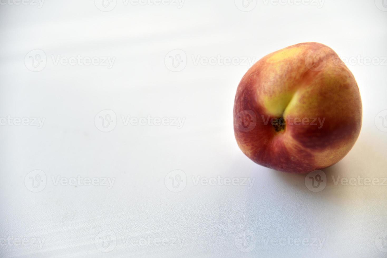 Yellow-red juicy peach nectarine on a white plate photo