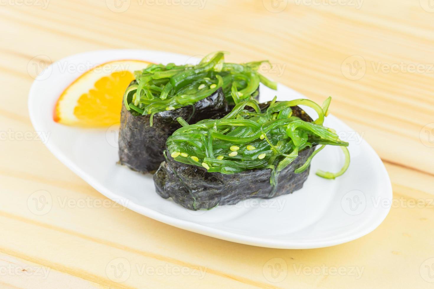 sushi with seaweed in a plate placed on a wooden floor photo