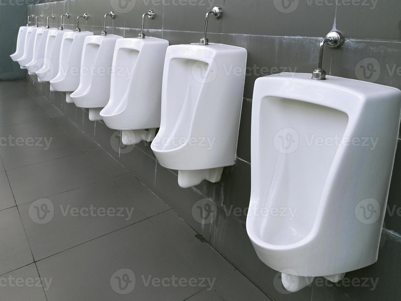 Close up row of urinal toilet blocks in public restroom photo