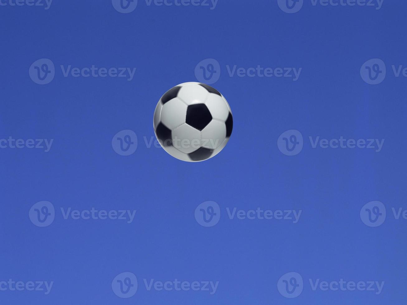 A soccer ball shot in the air with blue sky background photo