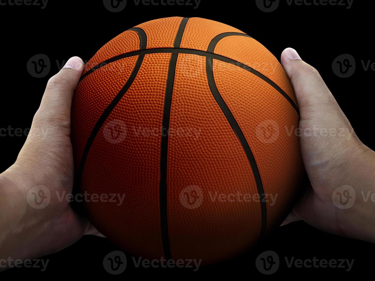 Basketball player holding a ball against black background photo