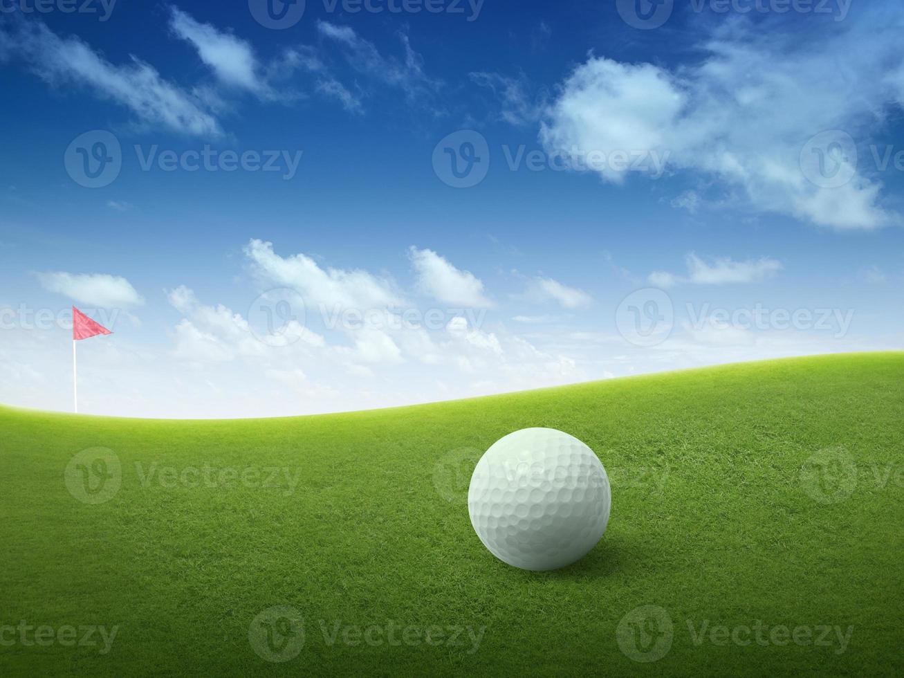 cerrar la pelota de golf en el campo de hierba verde y la bandera roja de golf en la calle verde con un hermoso cielo azul foto