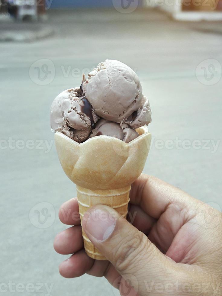 una mano de hombre sosteniendo un cono de helado sobre un fondo blanco foto