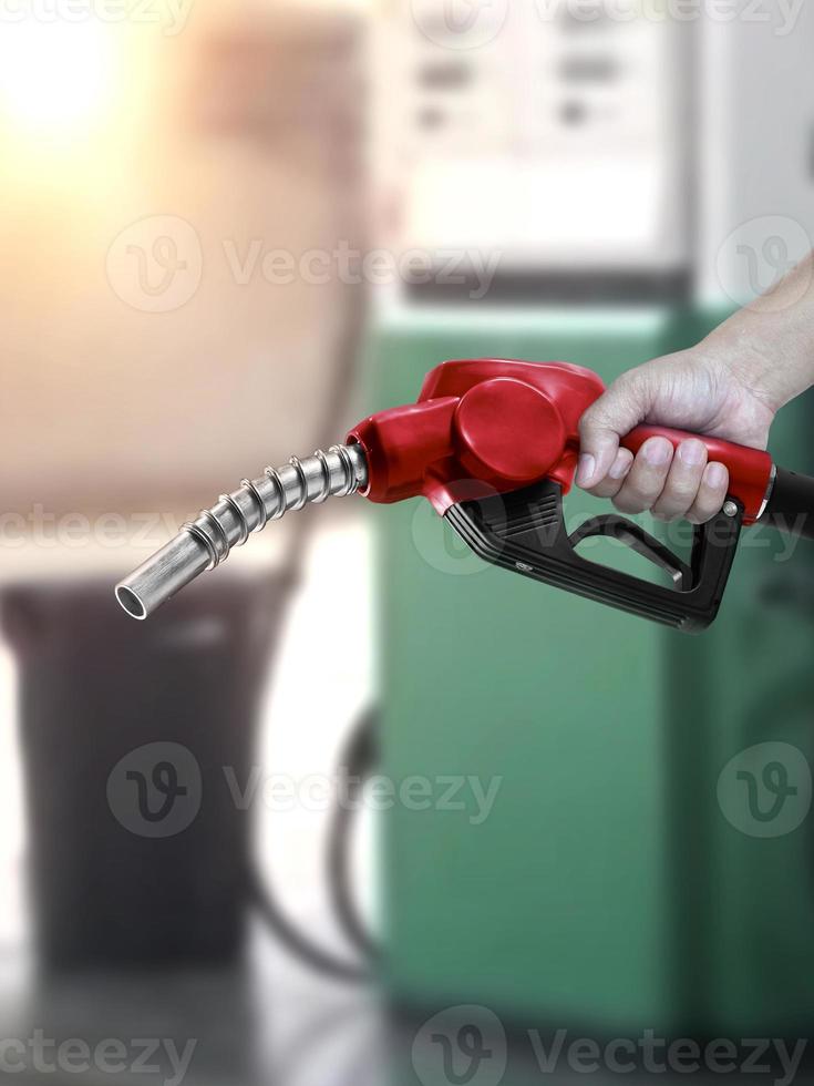 hombre que sostiene la boquilla de combustible en la gasolinera foto