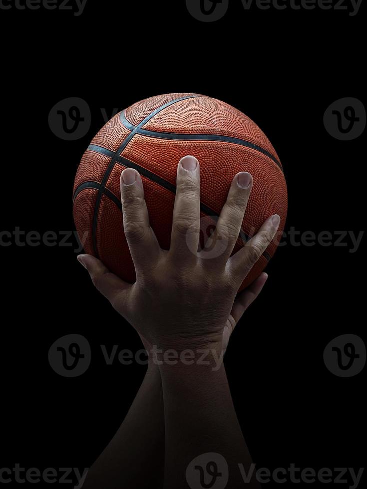 Basketball player holding a ball against black background photo