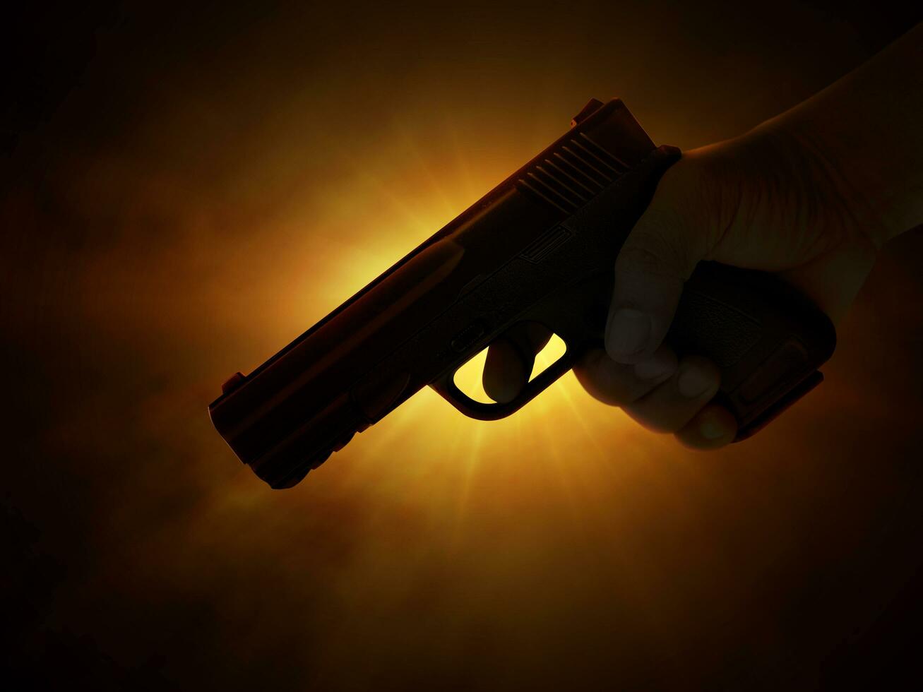 Male hand holding gun on black background with smoke  yellow orange red white  colored back lights photo