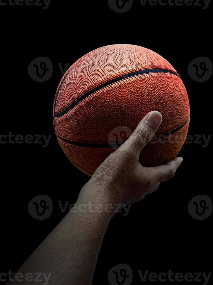 Basketball player holding a ball against black background photo