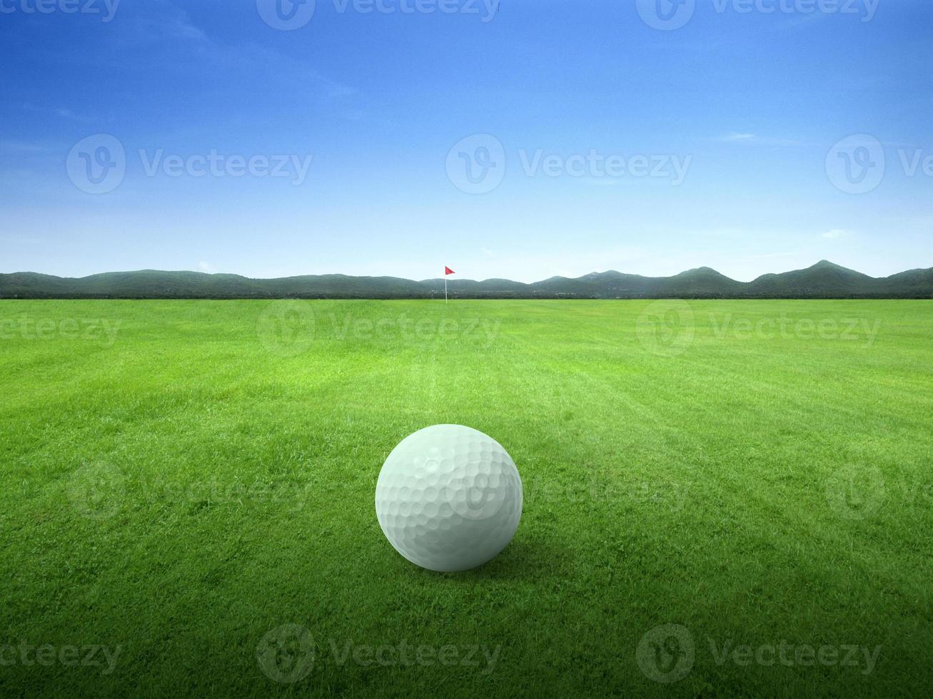 Close up golf ball on green grass field and red golf flag on green fairway with beautiful blue sky photo
