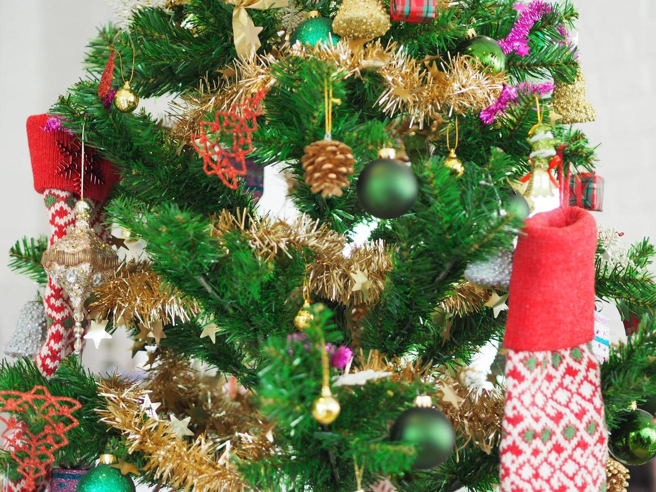 Christmas decorations green tree hanging, gold Gift box, green ball, brown Pine cones, socks, footwear, pink bell wrapped around it with a gold ribbon on white background photo