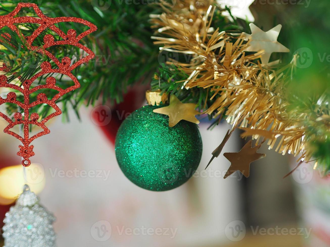 adornos navideños colgando del árbol verde, bola verde, calcetines, calzado, campana rosa envuelta alrededor con una cinta dorada sobre fondo blanco foto