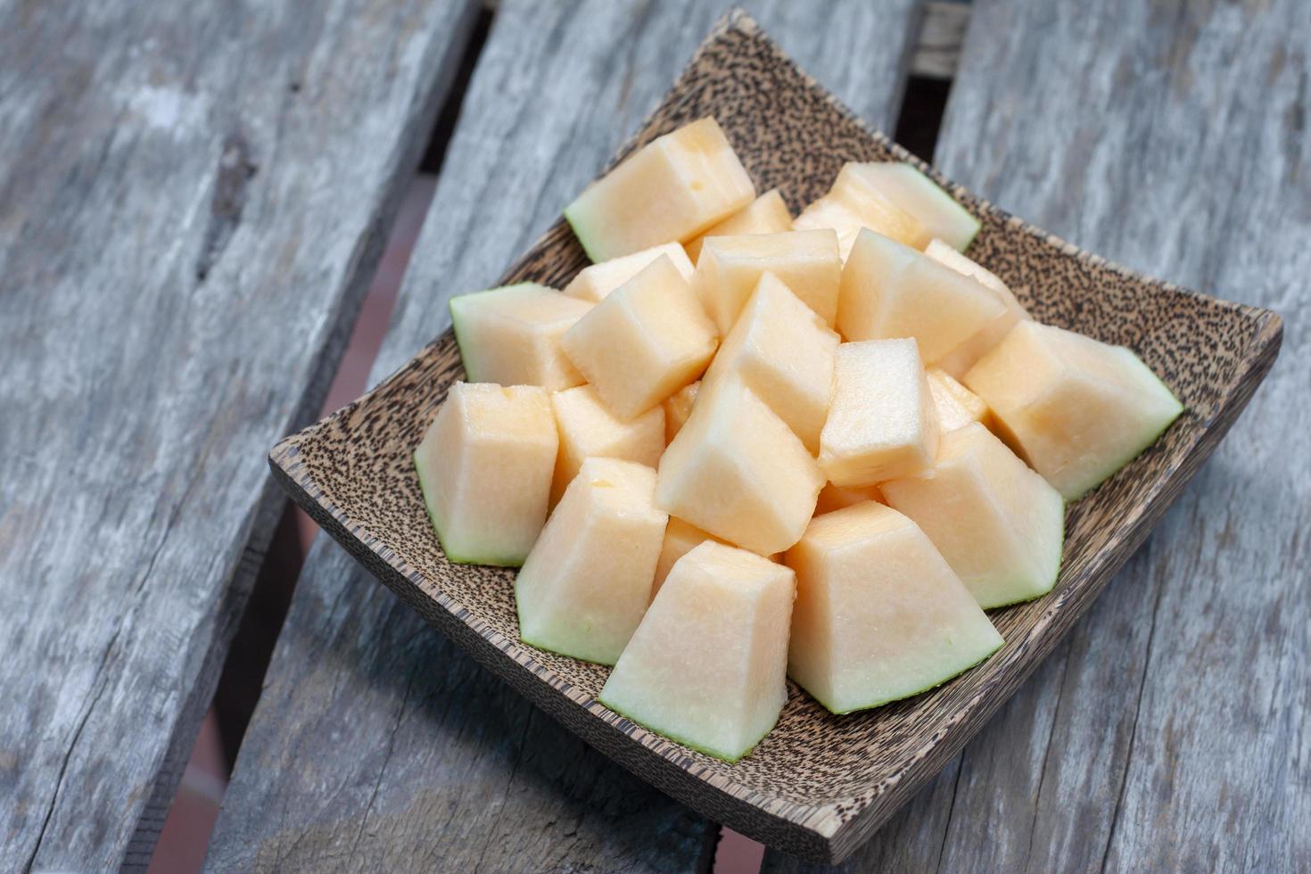 melón en rodajas en un plato de madera sobre un fondo de mesa antiguo. foto