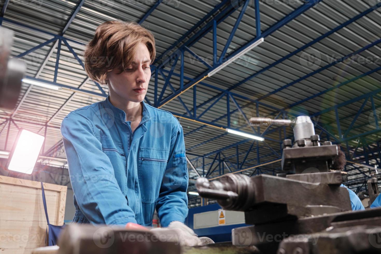 Professional young White female industry engineer worker works in safety uniform with metalwork precision tools, mechanical lathe machines, and spare parts workshop in the steel manufacturing factory. photo