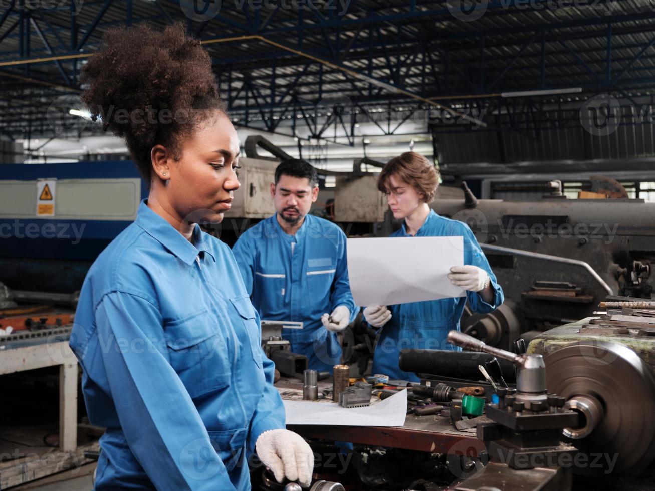 A professional young female industry engineer worker works in a safety uniform with metalwork precision tools, mechanical lathe machines, and spare parts workshop in the steel manufacturing factory. photo