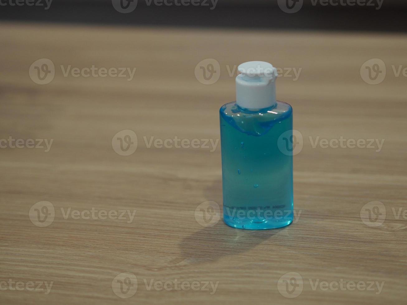 Hand Sanitizer, gel alcoholic mixture with gelatin in clear Plastic bottle with pump pushing wash clean dirty to prevent germs protect Contagious disease coronavirus covid-19, on wooden desk photo
