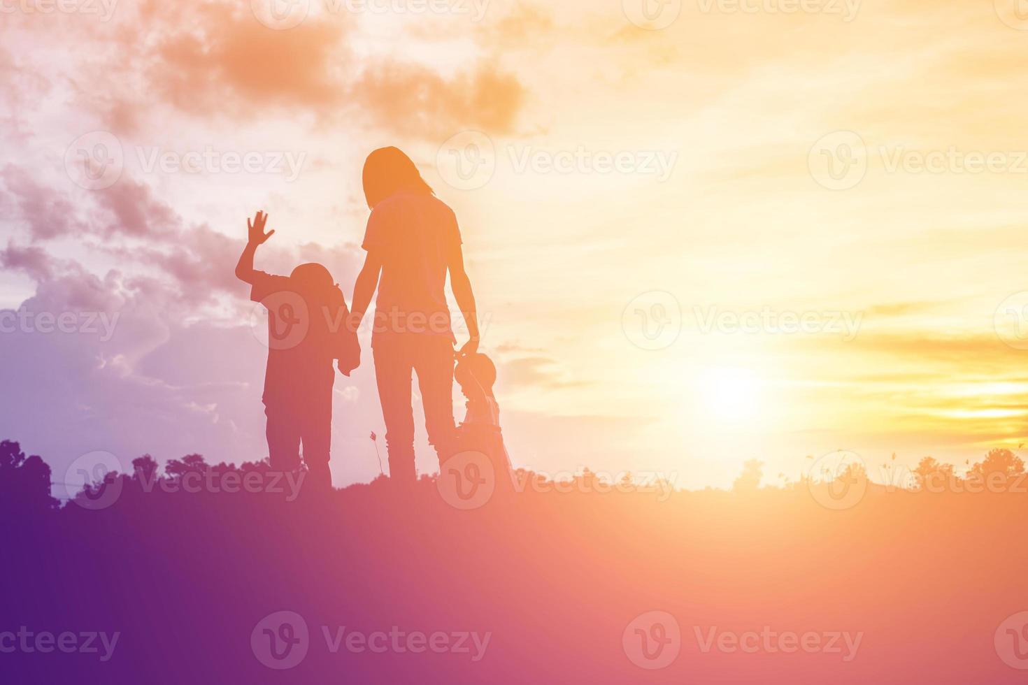 a silhouette of a happy young girl child the arms of his loving mother for a hug, in front of the sunset in the sky on a summer day. photo