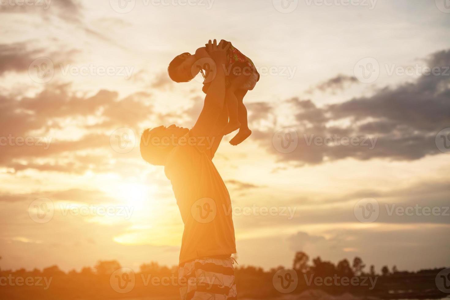 Father took the baby learn to walk at sunset. photo