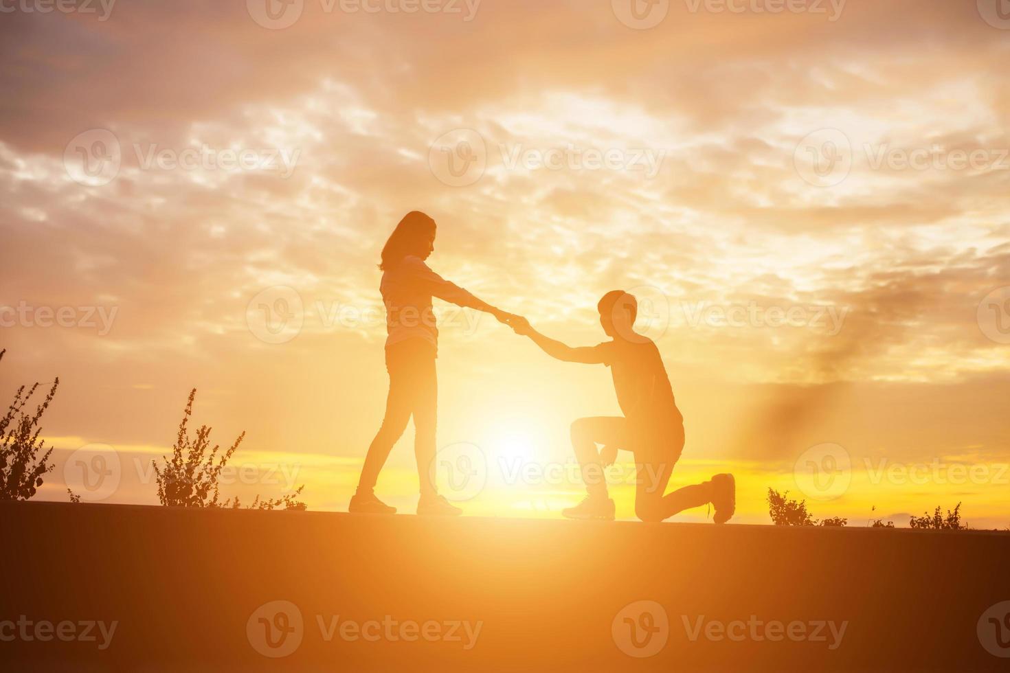 a silhouette of a man and woman holding hands with each other, walking together. photo