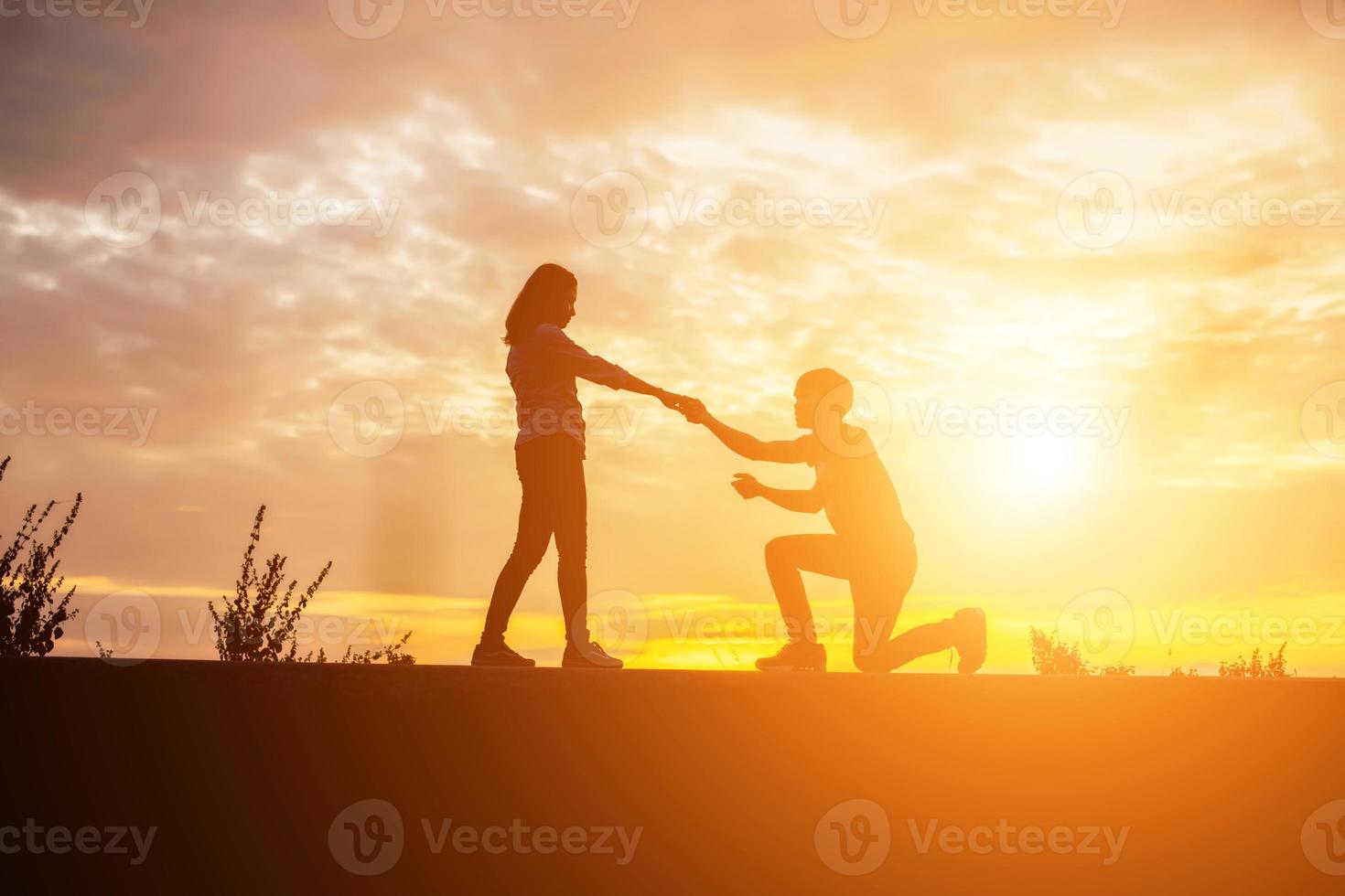 a silhouette of a man and woman holding hands with each other, walking together. photo