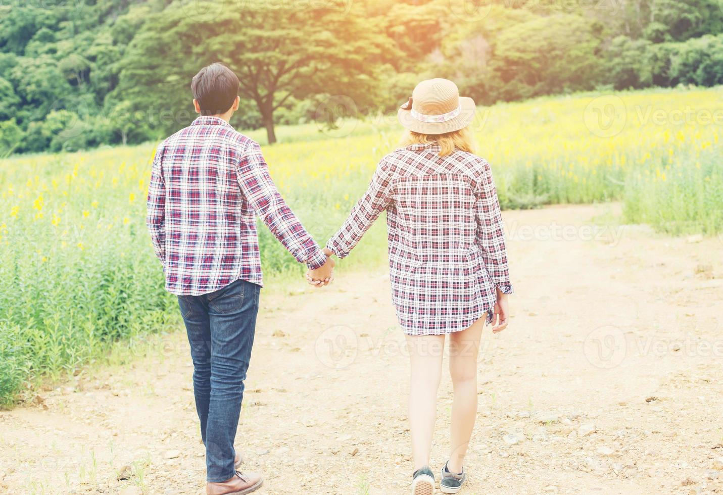 Young hipster couple relaxing in yellow flower field at summer. Enjoying with nature. photo