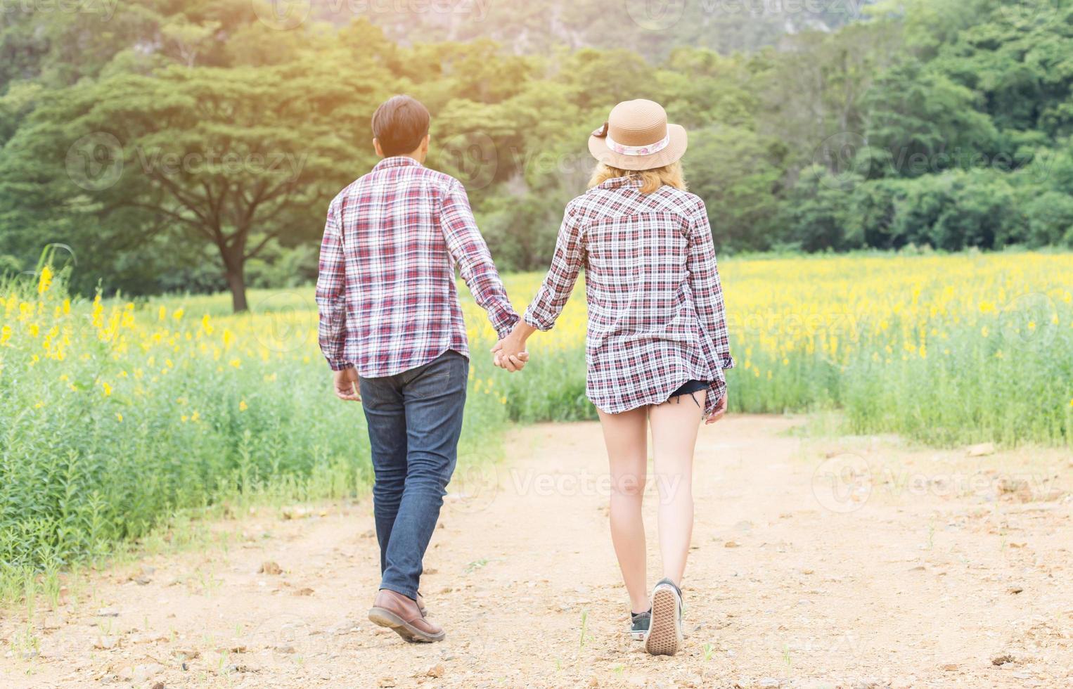 Young hipster couple relaxing in yellow flower field at summer. Enjoying with nature. photo