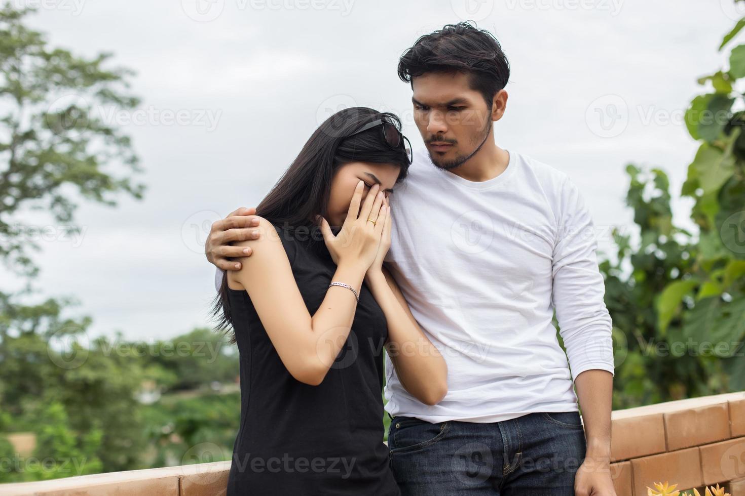 un joven y apuesto novio abrazando a su novia, ella estaba triste y molesta. foto