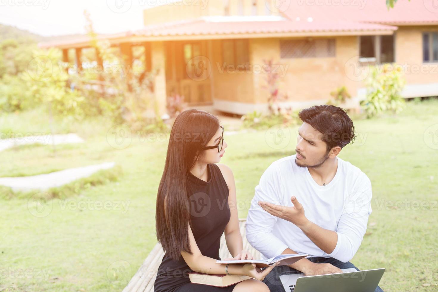 Young hipster couple enjoying a good read together while relaxing outdoors. photo
