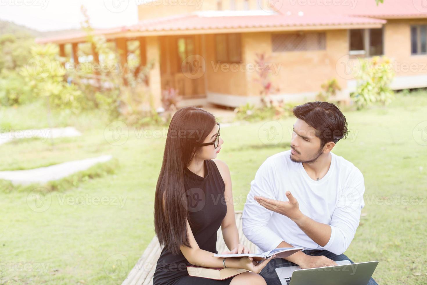 Young hipster couple enjoying a good read together while relaxing outdoors. photo