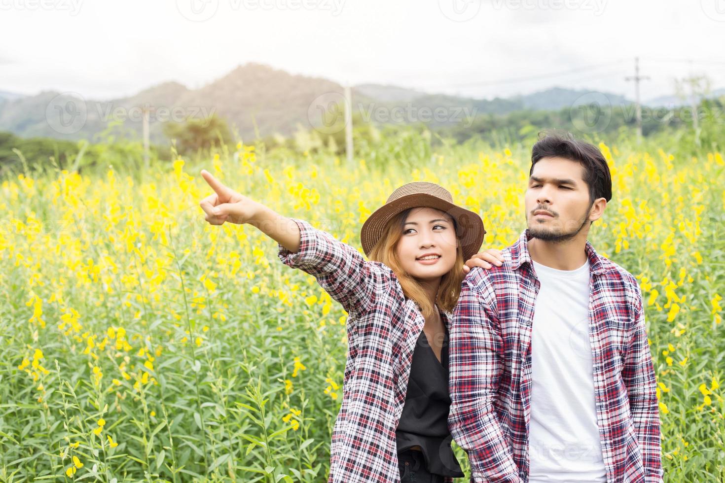 Young hipster couple relaxing in yellow flower field at summer. Enjoying with nature. photo