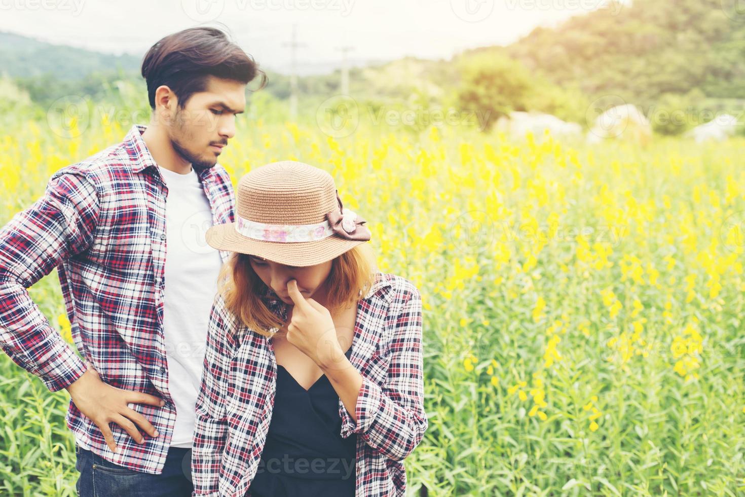 Young hipster couple relaxing in yellow flower field at summer. Enjoying with nature. photo