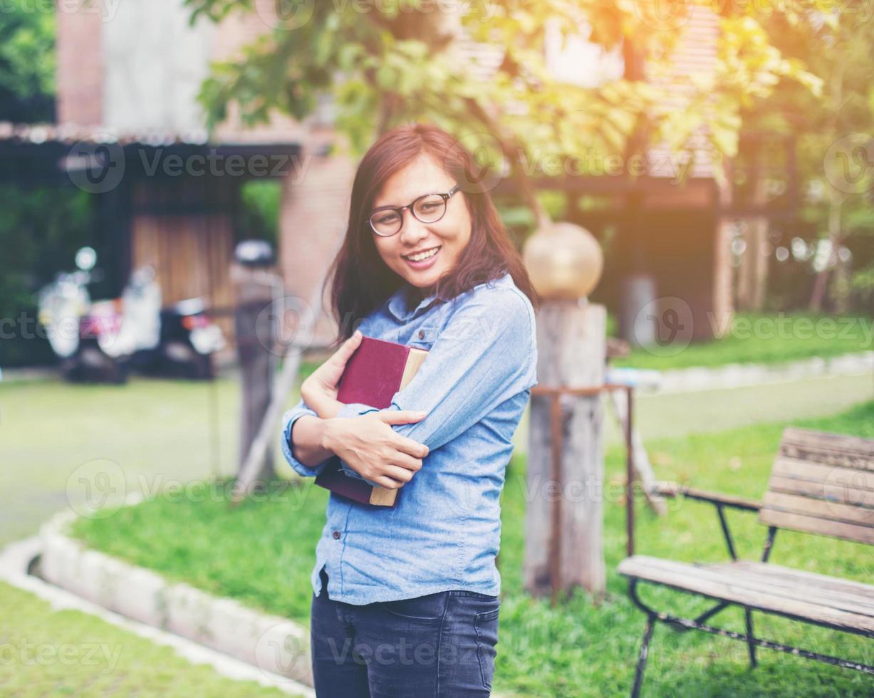Hipster charming girl relaxing in the park while read book, Enjoy nature around. photo