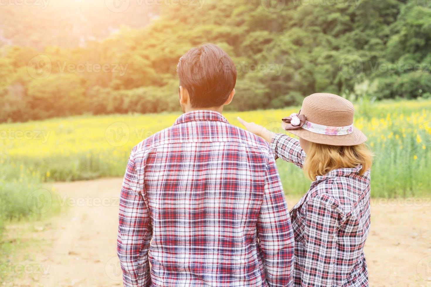 Young hipster couple relaxing in yellow flower field at summer. Enjoying with nature. photo