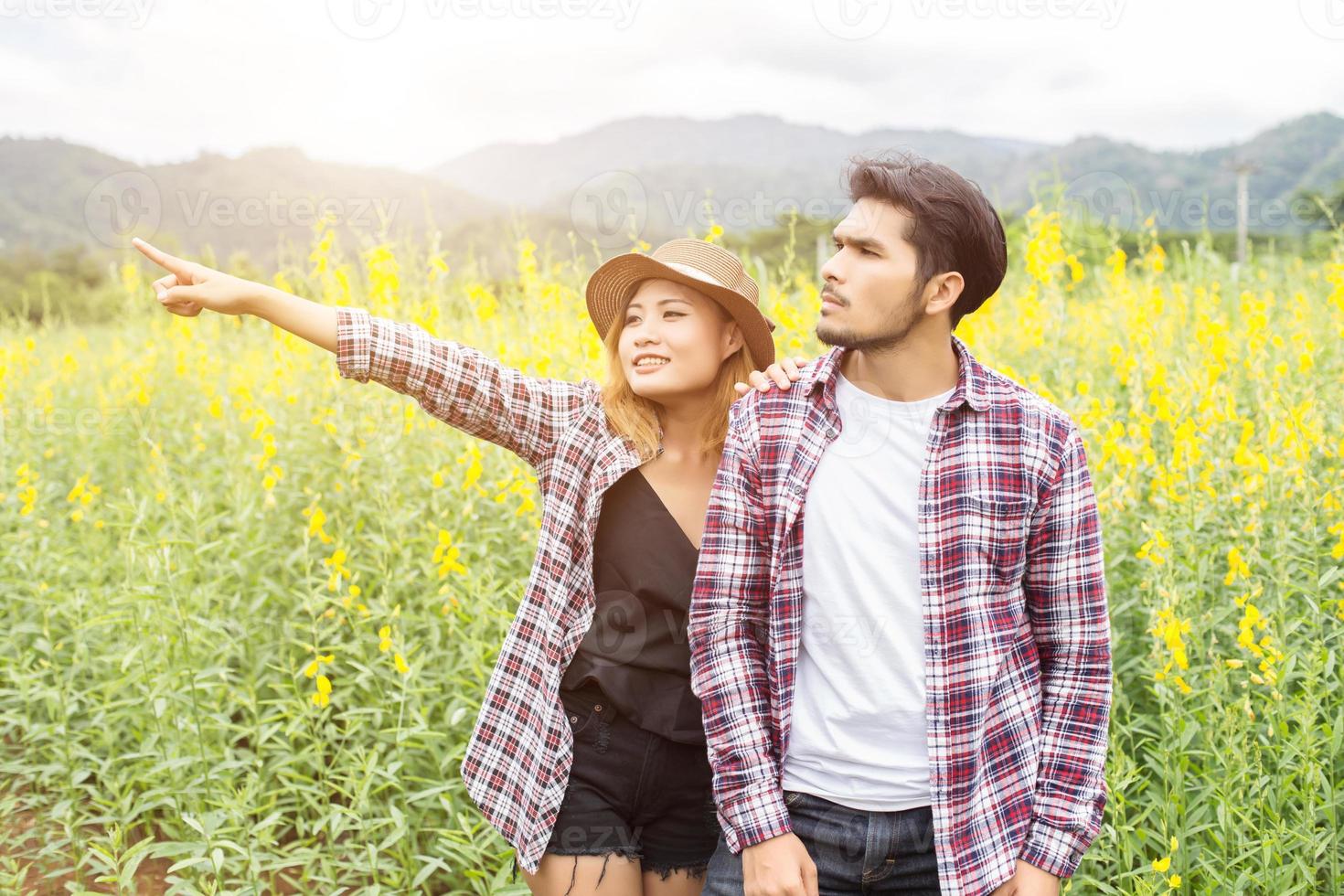 Young hipster couple relaxing in yellow flower field at summer. Enjoying with nature. photo