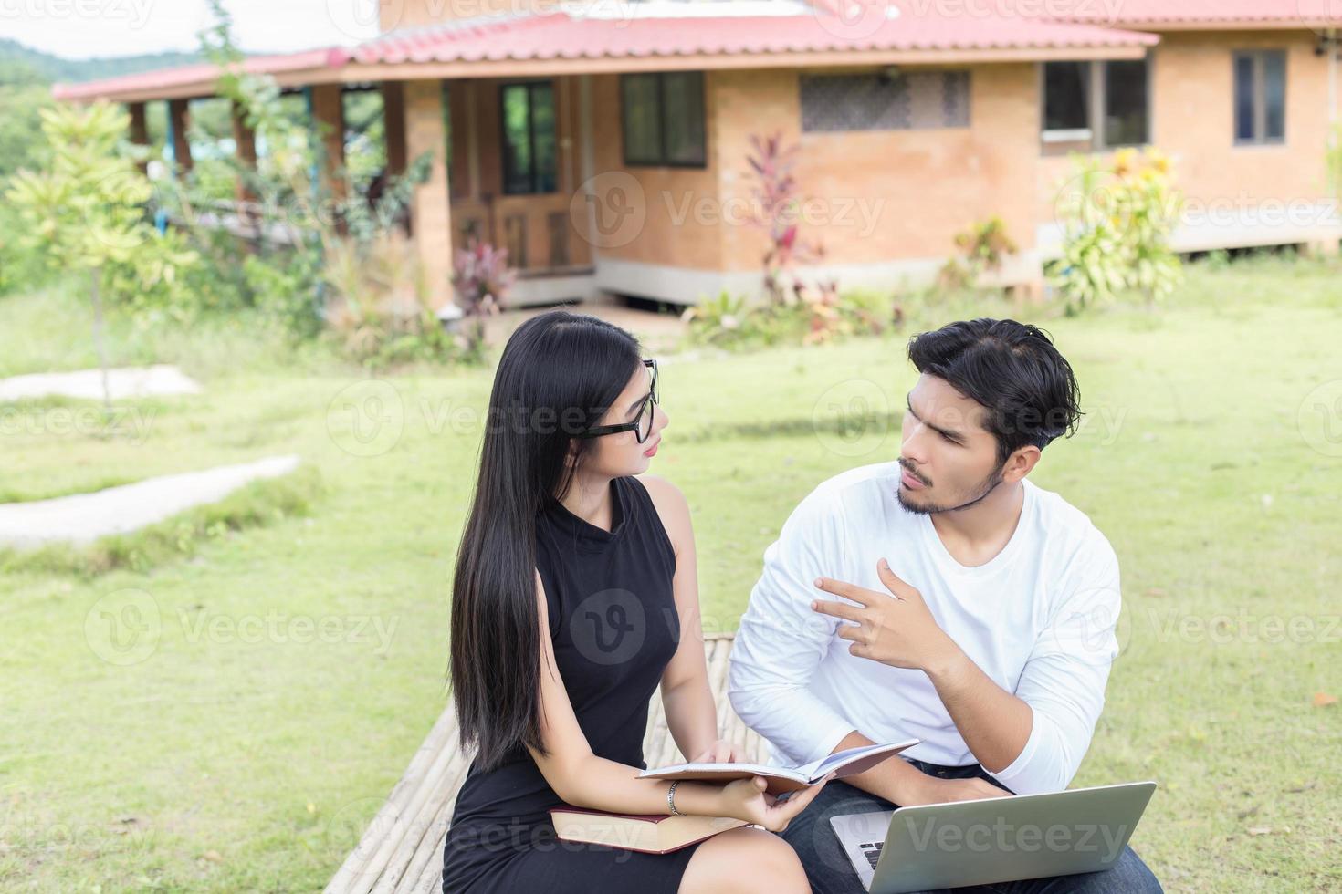 Young hipster couple enjoying a good read together while relaxing outdoors. photo