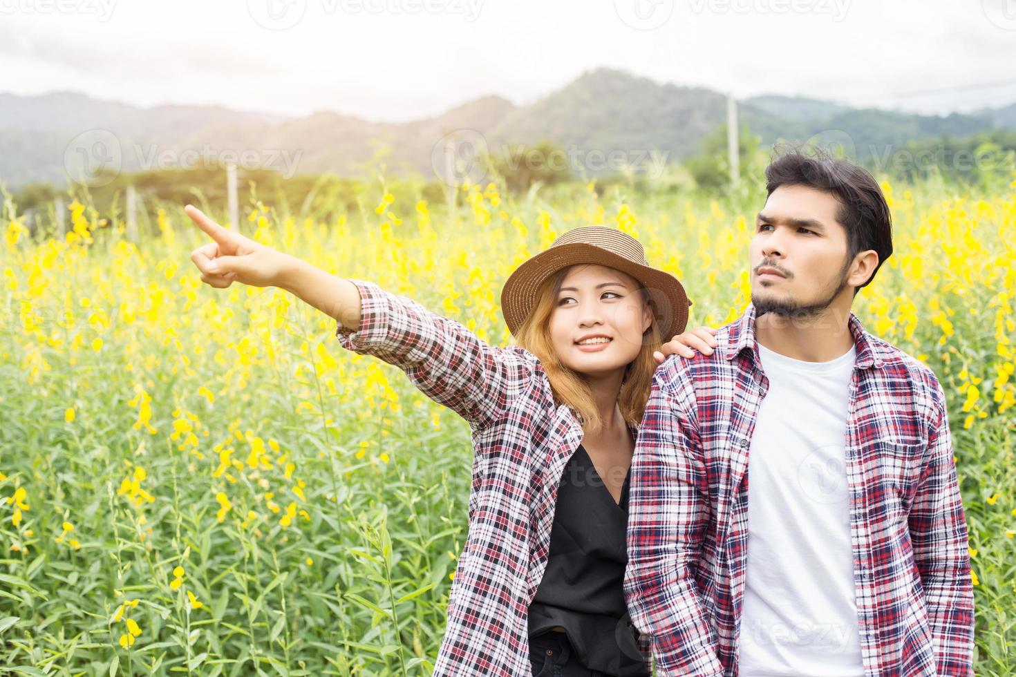 Young hipster couple relaxing in yellow flower field at summer. Enjoying with nature. photo