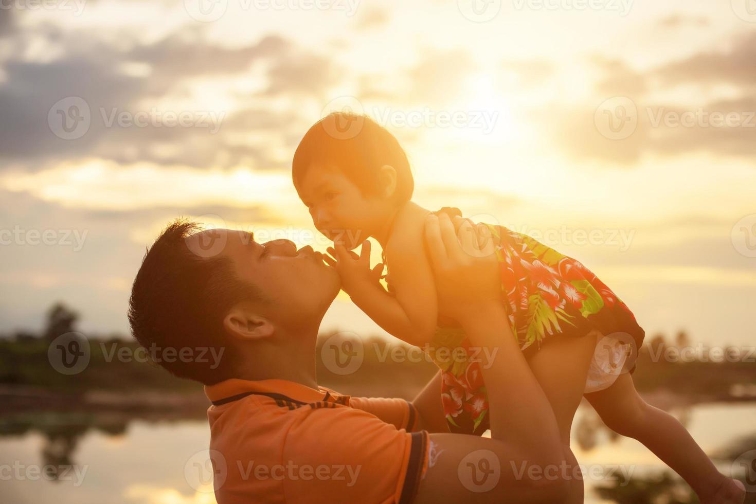 Father took the baby learn to walk at sunset. photo