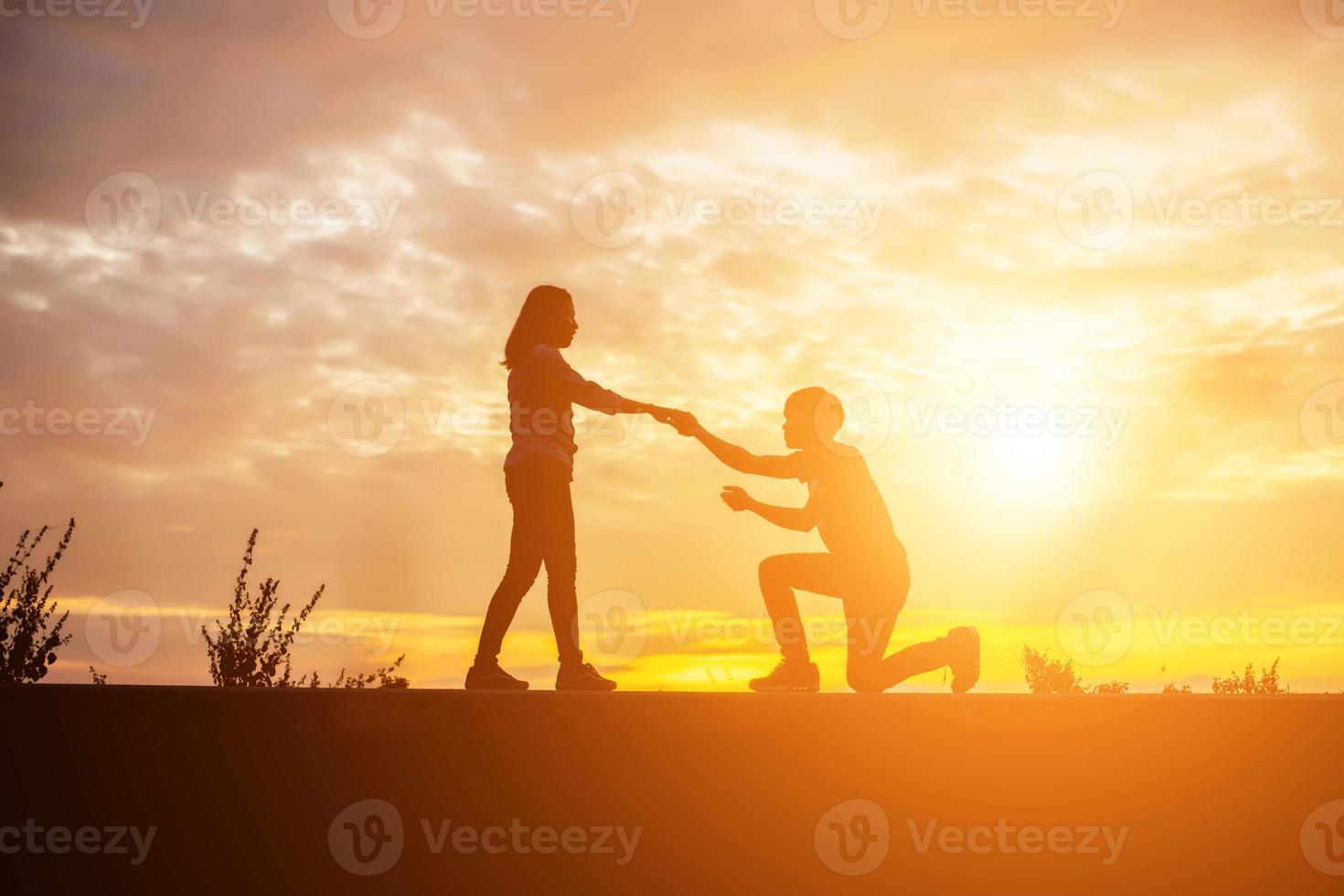 a silhouette of a man and woman holding hands with each other, walking together. photo