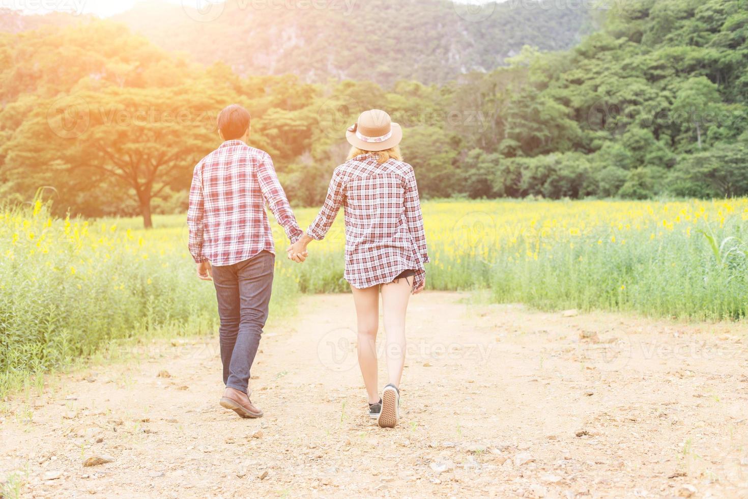 Young hipster couple relaxing in yellow flower field at summer. Enjoying with nature. photo