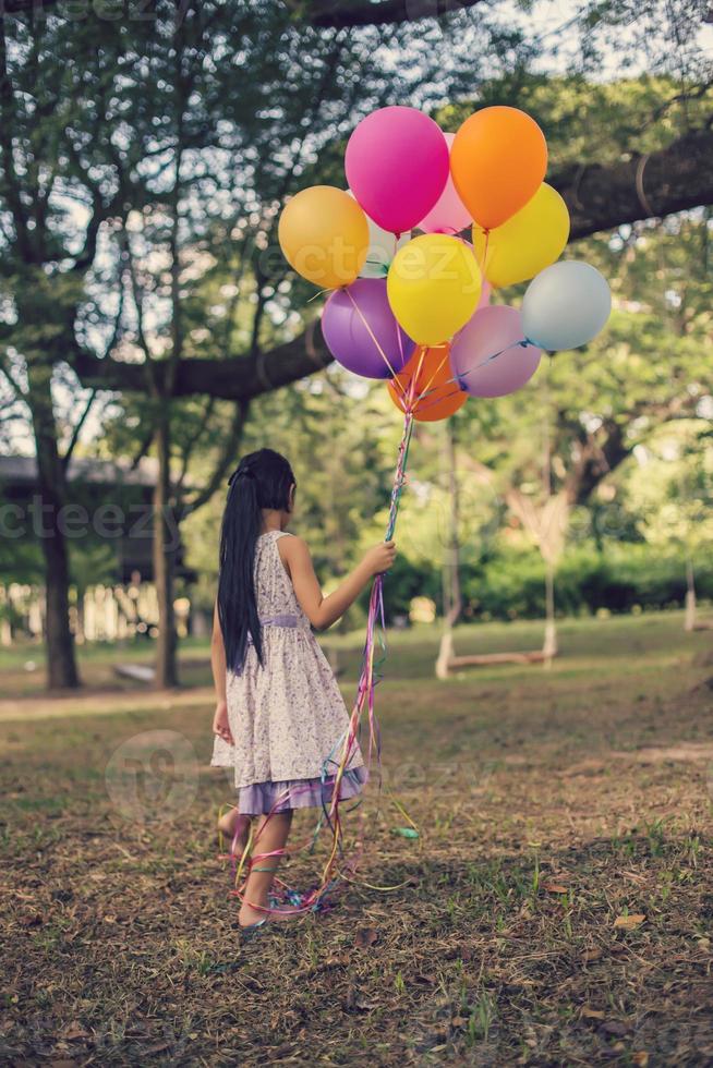 Little girl with balloons in a field photo