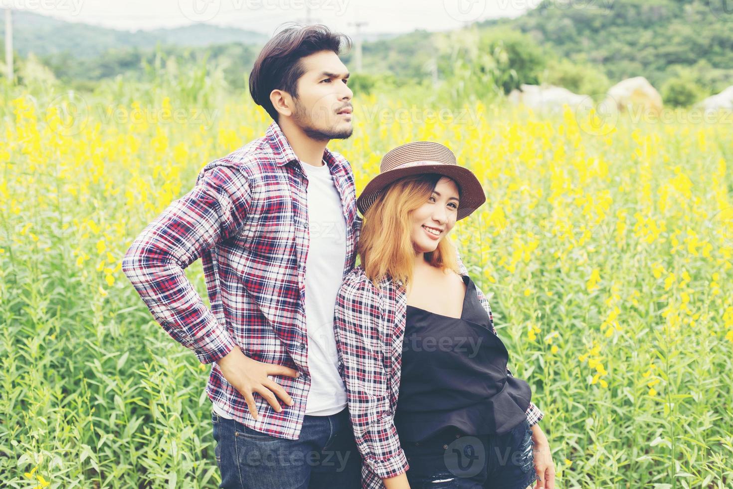 Young hipster couple relaxing in yellow flower field at summer. Enjoying with nature. photo