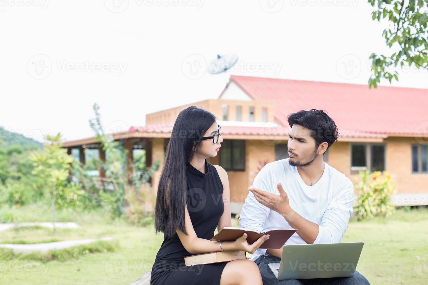 Young hipster couple enjoying a good read together while relaxing outdoors. photo