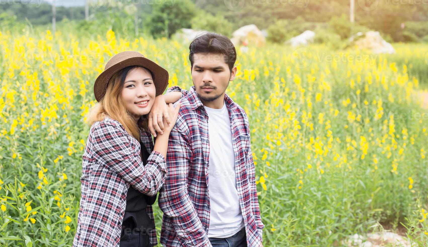 Young hipster couple relaxing in yellow flower field at summer. Enjoying with nature. photo
