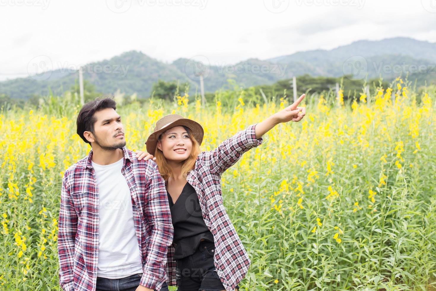 Young hipster couple relaxing in yellow flower field at summer. Enjoying with nature. photo