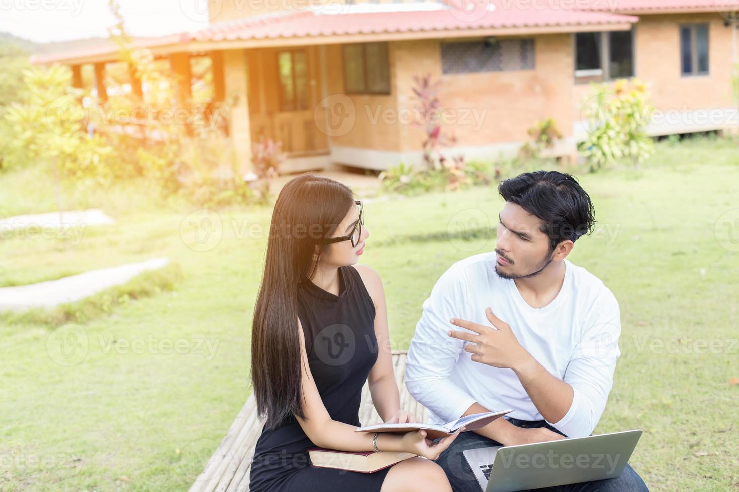 Young hipster couple enjoying a good read together while relaxing outdoors. photo