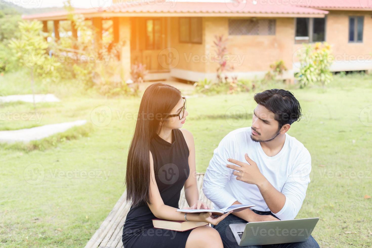 Young hipster couple enjoying a good read together while relaxing outdoors. photo