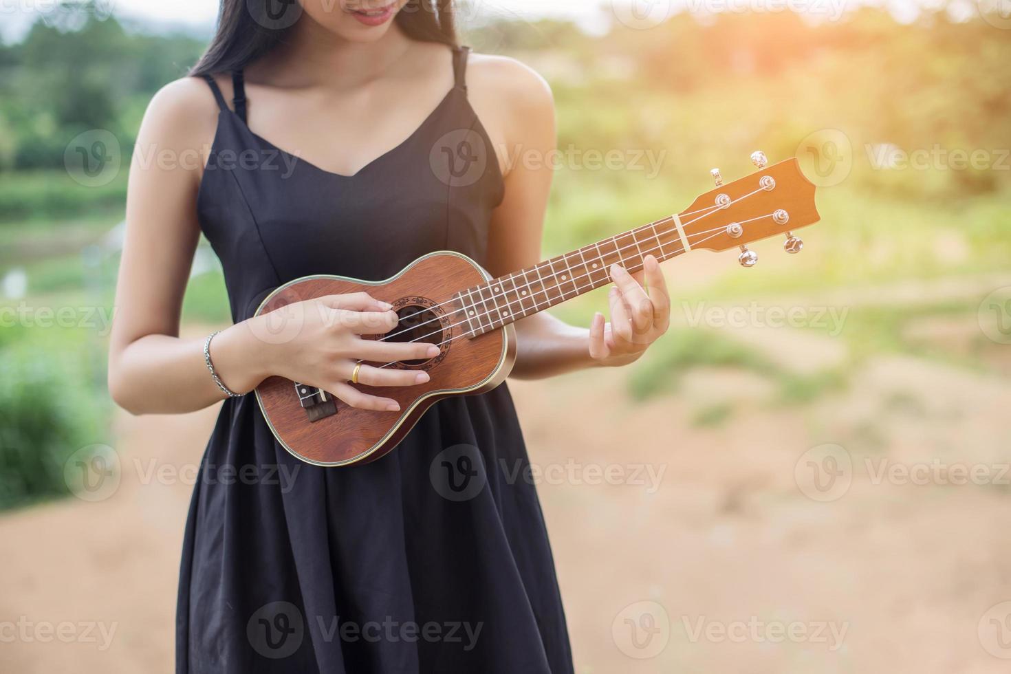 hermosa mujer sosteniendo una guitarra en su hombro, parque natural de verano afuera. foto