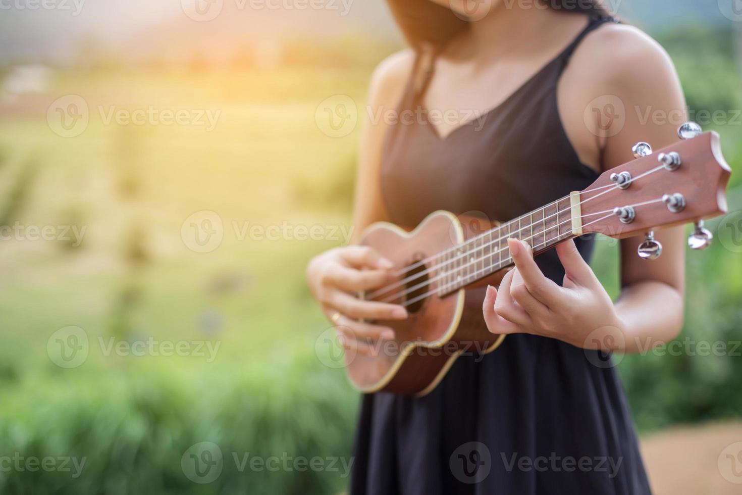 hermosa mujer sosteniendo una guitarra en su hombro, parque natural de verano afuera. foto